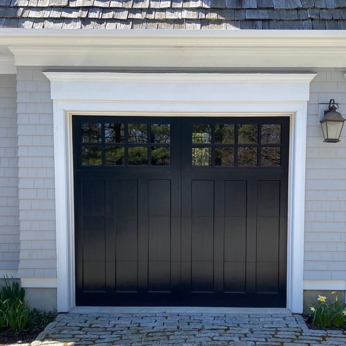 Custom-designed garage door with a sleek black finish and upper window panels for added style and natural light. This door was installed to enhance the aesthetic appeal and functionality of the property, offering both durability and modern elegance.