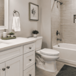 This bathroom remodel features a clean, timeless design with a bright white vanity, quartz-style countertop, undermount sink, and classic shaker-style cabinetry. The updated tub and shower area includes neutral wall tile, a built-in shower niche, and modern brushed fixtures for a polished, functional finish. Soft wall colors, coordinated flooring, fresh trim, and simple decorative accents create a warm and inviting space. This project highlights quality craftsmanship, thoughtful design, and atte