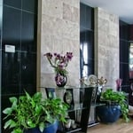 a tropical asian style entry with hardwood floors, a glass top entry table and flower pots