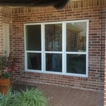 an exterior view of a white trimmed window with a red brick home exterior