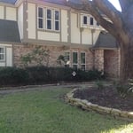 a tudor style home exterior with beige brick siding, tan trim and off white stucco exterior