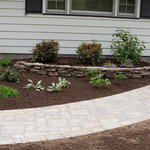 dry stacked retaining wall with brown mulch and bushes for a manicured front yard landscape