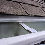 a close up view of an asphalt shingled roof with a white rain gutter
