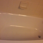 Large white porcelain tub with white tile wall.