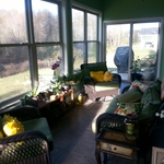 Traditional sunroom with dark tile flooring, green wall paint, white wood trim, and brown wicker patio furniture