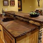 a rustic style kitchen with rough edged countertops and light wood cabinetry