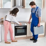 Housewife Showing Damaged Oven To Worker