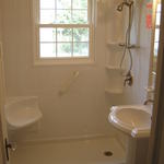 Walk-in shower with corner seat and tower shelf