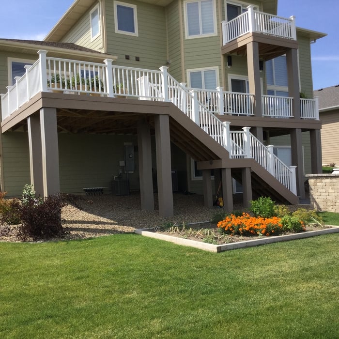 an open backyard composite wood deck with staircase to backyard