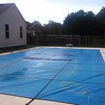Blue pool cover and textured concrete pool deck