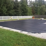 Pool cover, concrete deck and vinyl picket fence