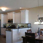Eat in kitchen with white cabinetry, black granite countertops and stainless steel appliances