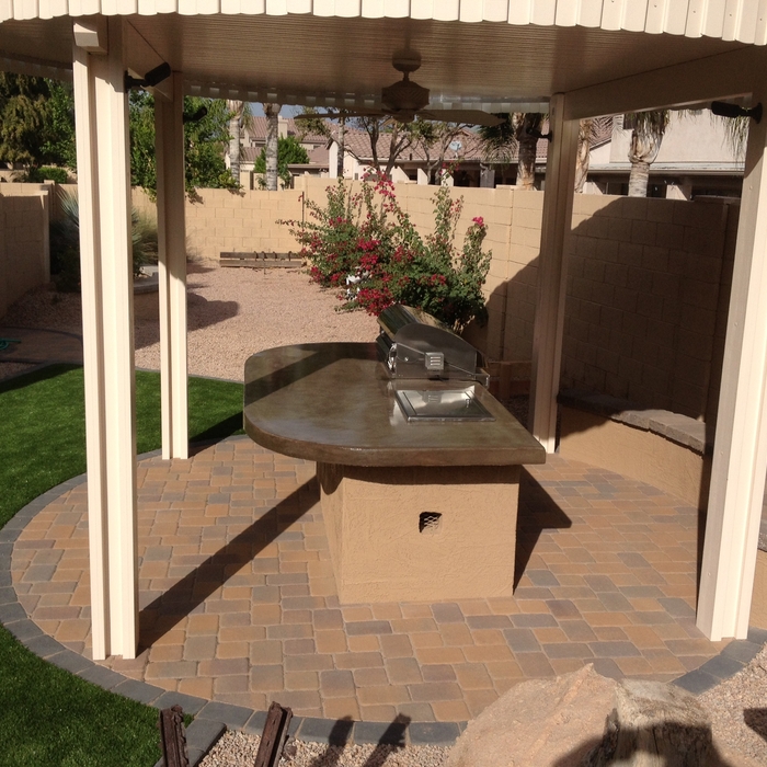 Paver patio with low sitting wall and patio cover over a small outdoor kitchen