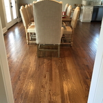 Traditional dining area with stained wood flooring, high back chairs, and box pendant dining chandelier
