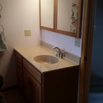Traditional bathroom with solid surface countertop, wood framed vanity mirror, and stained wood vanity
