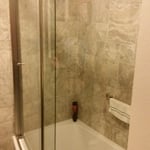 Traditional bathroom with beige tile wall, curved shower door, and brown tile accent
