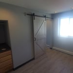 Renovated bedroom with barn door leading to closet